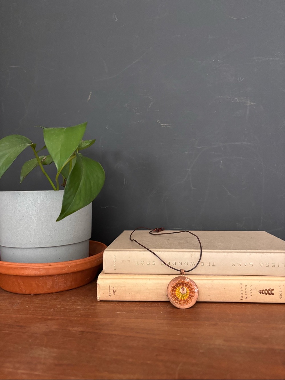 Copper mandala necklace with a spiral design and a brown leather cord